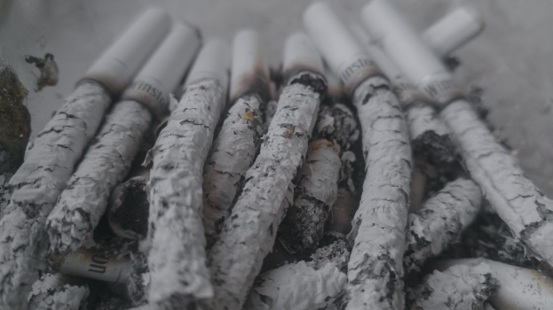 Ein unordentlicher Haufen von aschfarbenen Zigaretten auf einem Tisch.