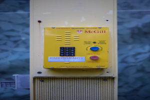 Gelber Notrufhörer an einer Gebäudewand mit Tasten und Text, entworfen für Notrufe.