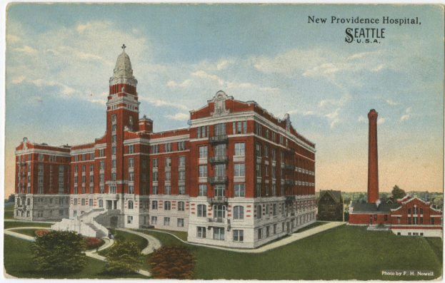 Eine Vintage-Postkarte zeigt das New Providence Hospital in Seattle, Washington, mit einem mehrstöckigen Backsteingebäude mit Fenstern, einer Vortreppe mit Geländern, umgeben von Bäumen, Gras und einem bewölkten Himmel, sowie gedrucktem Text.