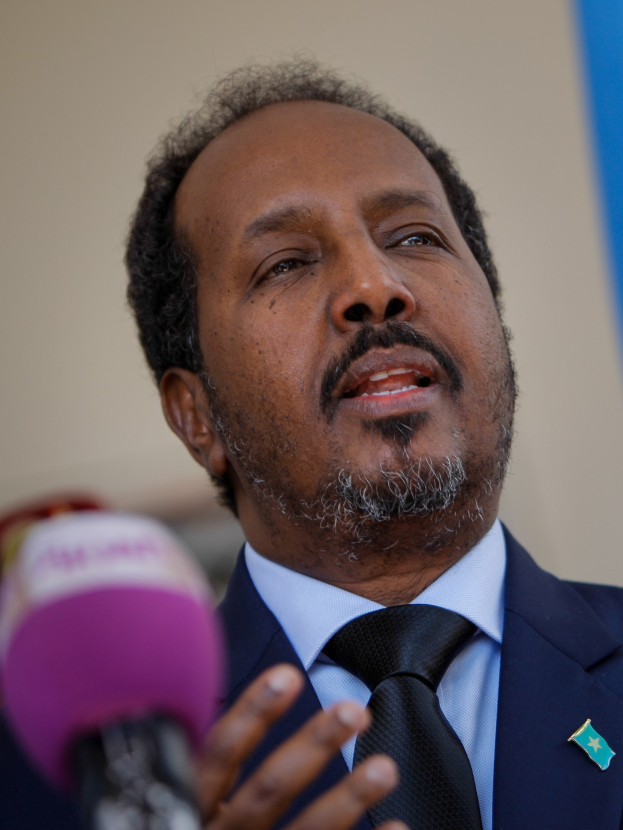 Ein Mann im Anzug und Krawatte spricht in ein Mikrofon, wahrscheinlich vor einem Publikum als Politologe.