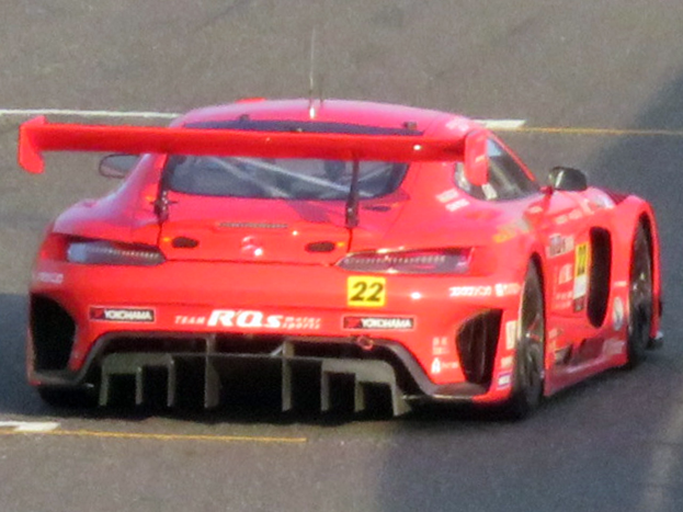 Roter Porsche 911 GTS Rennauto mit großer Heckflosse und Spoiler auf einer Rennstrecke.