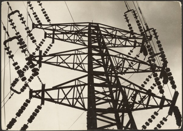 Ein Schwarz-Weiß-Foto einer Hochspannungsleitung mit einem Turm und Drähten im Vordergrund und einem Himmel im Hintergrund, mit Text am unteren Bildrand.