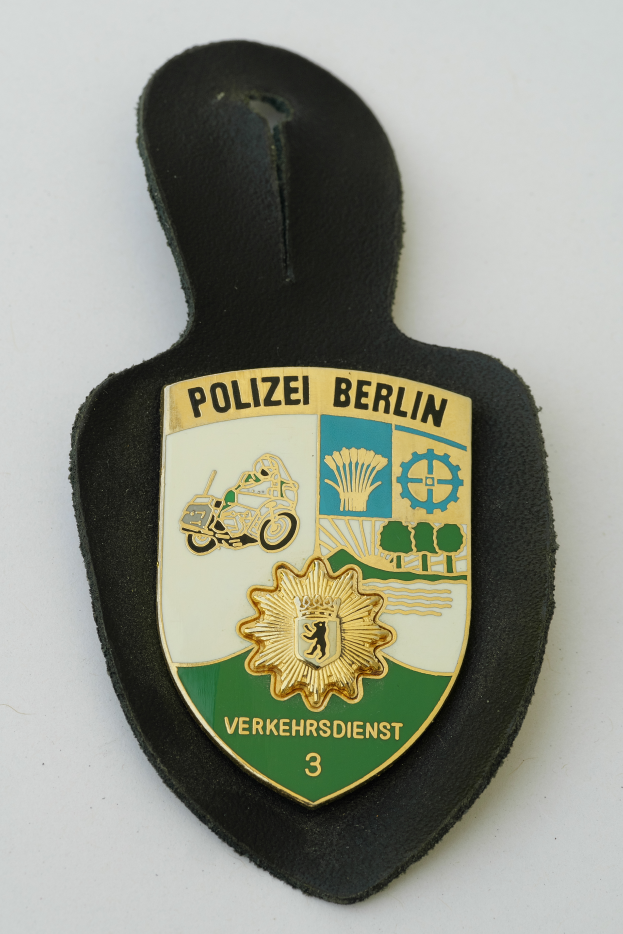 Ein Polizeistern mit der Aufschrift "Polizei Berlin" auf einem blauen Hintergrund, einem weißen Stern in der Mitte und einem weißen Rand.