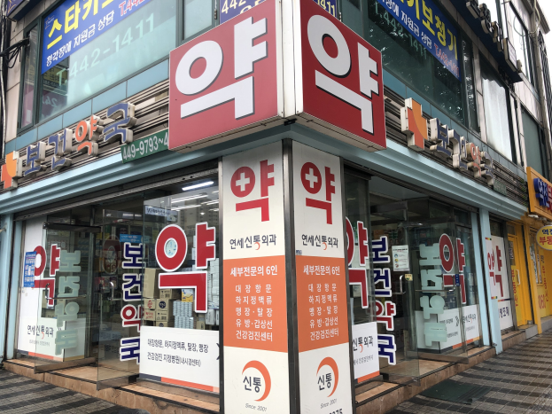 Außensicht eines modernen Glaswand-Apothekengebäudes in Seoul, Südkorea, mit einer Beschriftung, die es als die erste Apotheke der Stadt identifiziert.