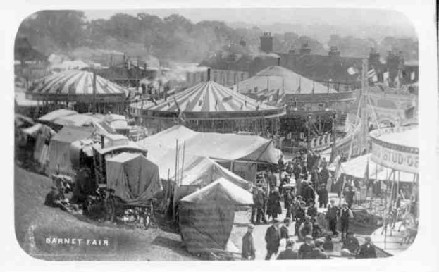 Schwarzes und weißes Foto eines Volksfests mit Zelten, Menschen, Karren, Pfählen, Bäumen und Gebäuden, beschriftet mit "Barnet Fair, London, England" unten.