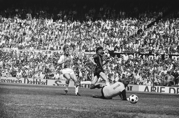 Schwarzes Foto von Männern, die Fussball auf einem Feld spielen, mit Zuschauern im Hintergrund und einem Banner mit der Aufschrift "Bundesliga 1978-79 Ajax 1-1 Hannover 96".