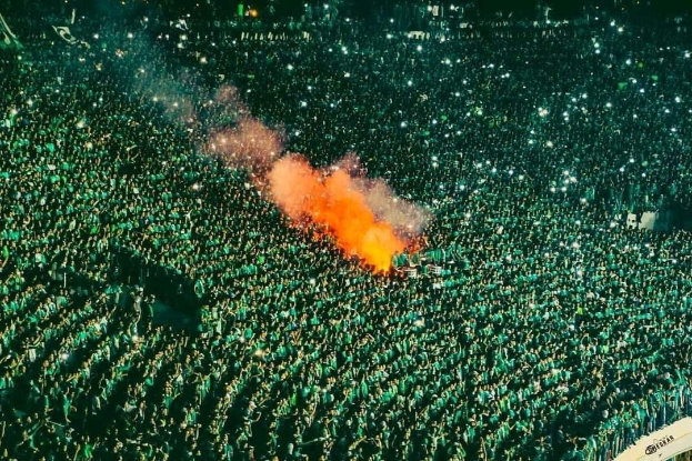 Große Menschenmenge in einem Stadion mit einem Feuer in der Mitte.