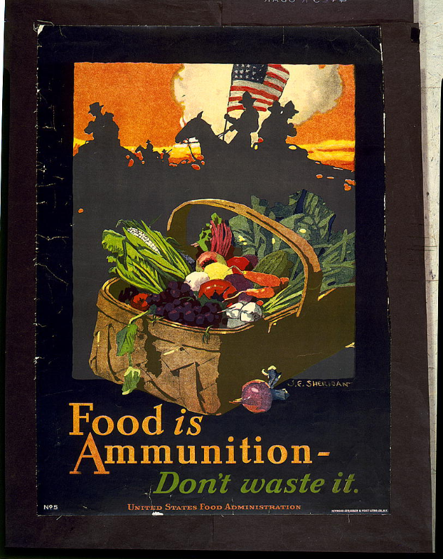 Ein Plakat an einer Wand mit einem Korb voller Karotten, Kartoffeln, Zwiebeln und Paprika, mit der Aufschrift "Food is Ammunition - Don't Waste It" in fetter, schwarzer Schrift.