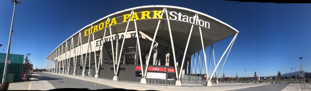 Großes modernes Stadion namens "Europa-Park Stadion" in Barcelona, Spanien, umgeben von Pfählen, Lichtern, Bäumen und einem Zaun.