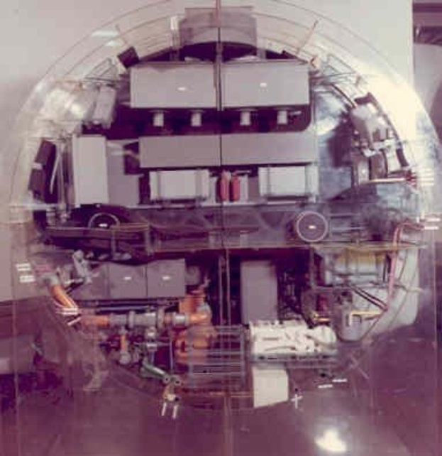 Großes zylindrisches Metallteil innerhalb eines Kernreaktor-Betongebäudes, umgeben von einer Schutzmauer mit sichtbarem Bodenbelag.