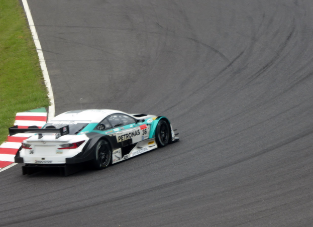 Ein Mercedes-AMG GT3-Rennwagen auf einer Rennstrecke mit Text auf der Karosserie und Gras links.