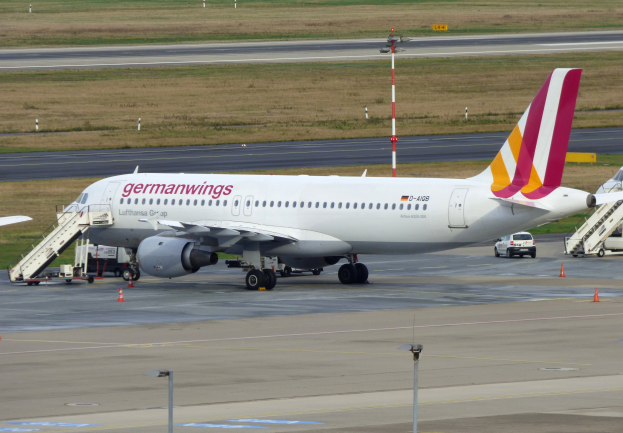 Ein geparktes Airbus A320-200-Flugzeug der Germanwings am Frankfurter Flughafen, mit Fahrzeugen, Verkehrskegeln, Pfählen und Gras im Hintergrund.
