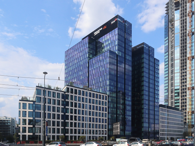 Zentrale der Deutschen Bank in Frankfurt, Deutschland, ein großes Gebäude mit vielen Fenstern, umgeben von Straßeninfrastruktur und Fahrzeugen.